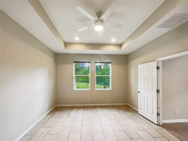 empty room with a tray ceiling, baseboards, visible vents, ceiling fan, and recessed lighting