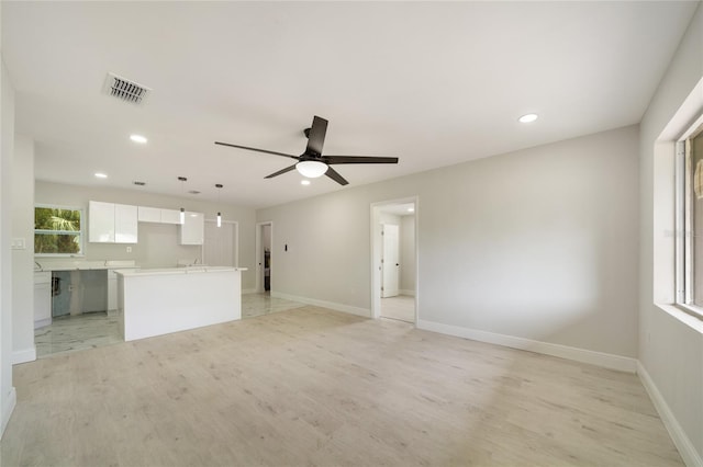 unfurnished living room featuring visible vents, baseboards, and plenty of natural light