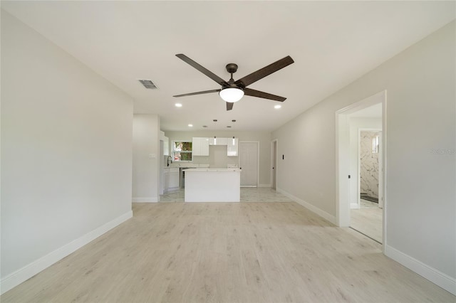 unfurnished living room featuring visible vents, light wood-style flooring, a ceiling fan, and baseboards