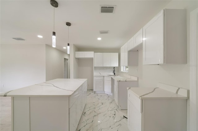 kitchen with light stone countertops, visible vents, a kitchen island, a sink, and marble finish floor