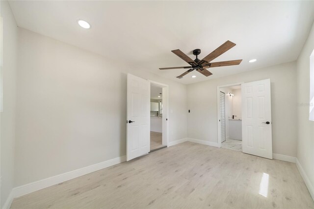 unfurnished bedroom featuring light wood-type flooring, ensuite bathroom, and ceiling fan