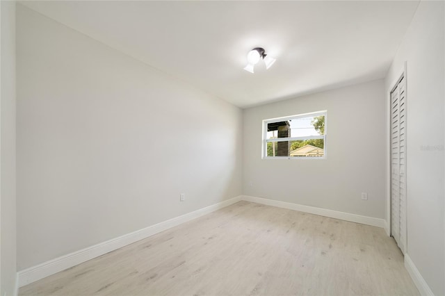 unfurnished room with baseboards and light wood-type flooring