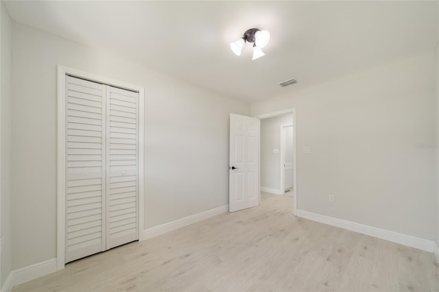 unfurnished bedroom with light wood-style floors, visible vents, a closet, and baseboards