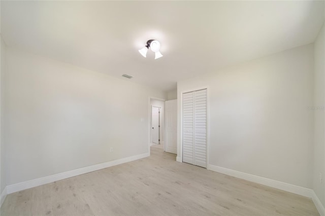 unfurnished bedroom featuring baseboards, visible vents, a closet, and light wood-type flooring