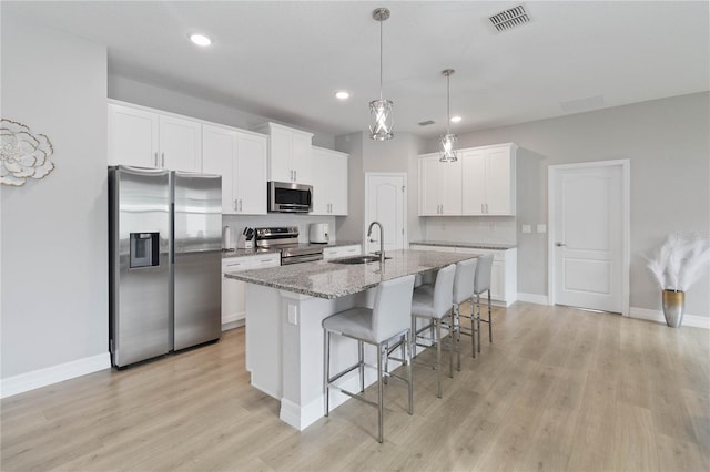 kitchen with light hardwood / wood-style flooring, a kitchen island with sink, stainless steel appliances, sink, and white cabinetry