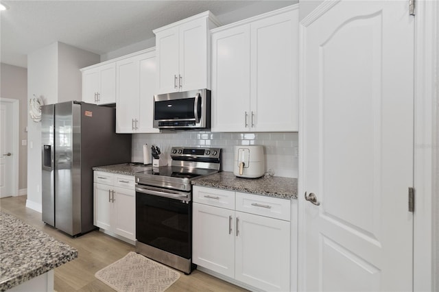 kitchen featuring stone counters, light wood-type flooring, appliances with stainless steel finishes, and white cabinets