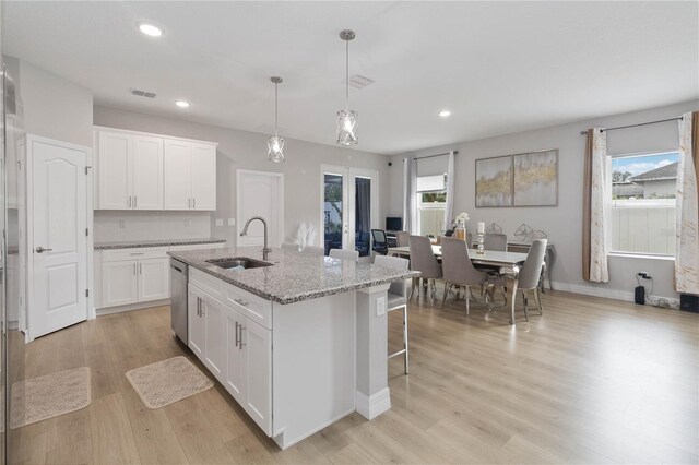 kitchen featuring white cabinets, dishwasher, light hardwood / wood-style floors, sink, and a center island with sink