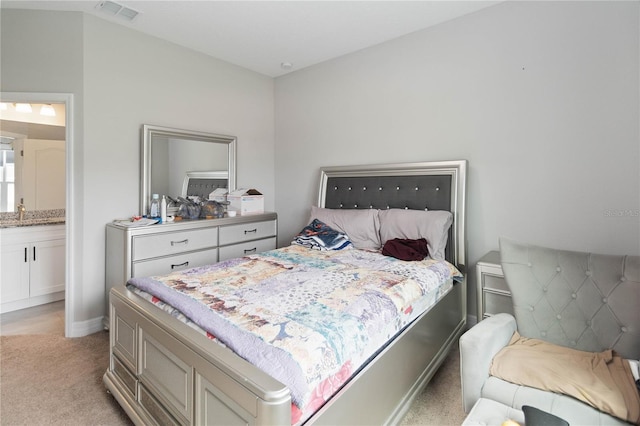 bedroom featuring light colored carpet, connected bathroom, and sink