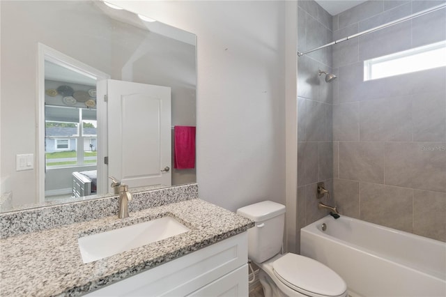 full bathroom featuring vanity, toilet, a healthy amount of sunlight, and tiled shower / bath