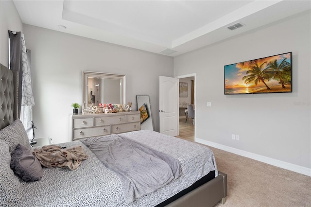 carpeted bedroom with a raised ceiling