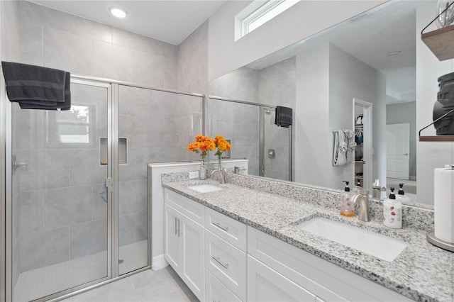 bathroom with tile patterned floors, a shower with door, and vanity