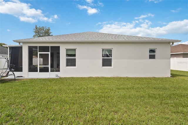 rear view of house with a lawn and a sunroom