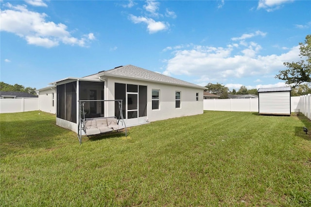 rear view of house with a yard, a storage unit, and a sunroom