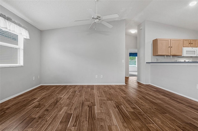 unfurnished living room with dark wood-type flooring, vaulted ceiling, ceiling fan, and a textured ceiling