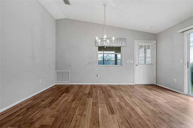 empty room featuring lofted ceiling, a healthy amount of sunlight, and hardwood / wood-style floors