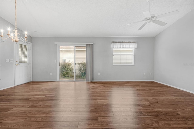 empty room featuring ceiling fan with notable chandelier, dark hardwood / wood-style flooring, and a textured ceiling