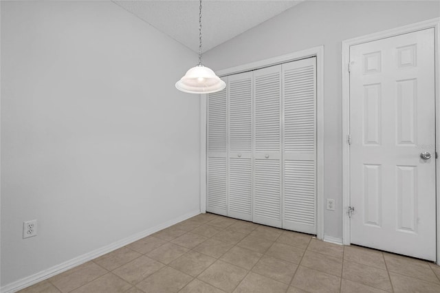 interior space featuring vaulted ceiling, a textured ceiling, light tile patterned flooring, and a closet