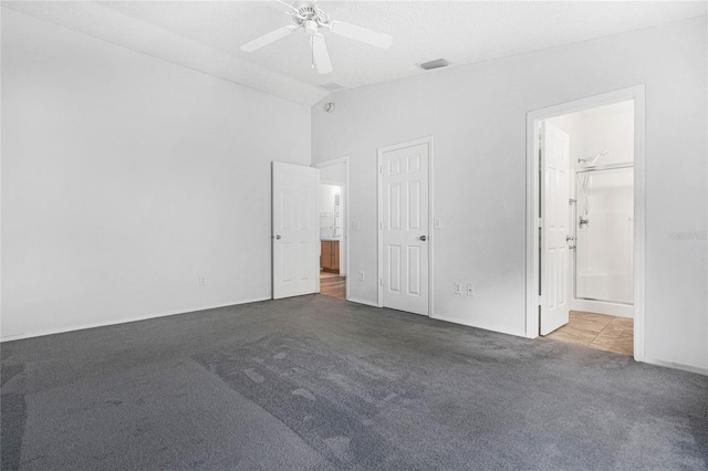 unfurnished bedroom featuring a textured ceiling, vaulted ceiling, light carpet, connected bathroom, and ceiling fan