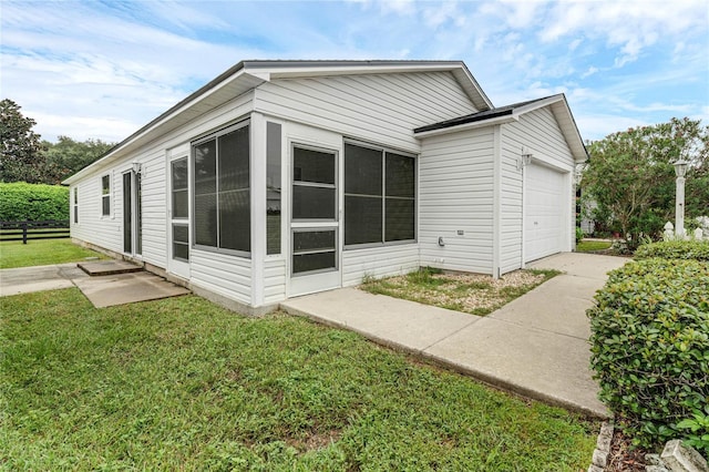 view of side of property featuring a garage, a sunroom, and a yard