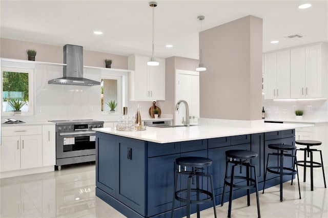 kitchen featuring stainless steel range with electric stovetop, pendant lighting, white cabinetry, decorative backsplash, and wall chimney range hood