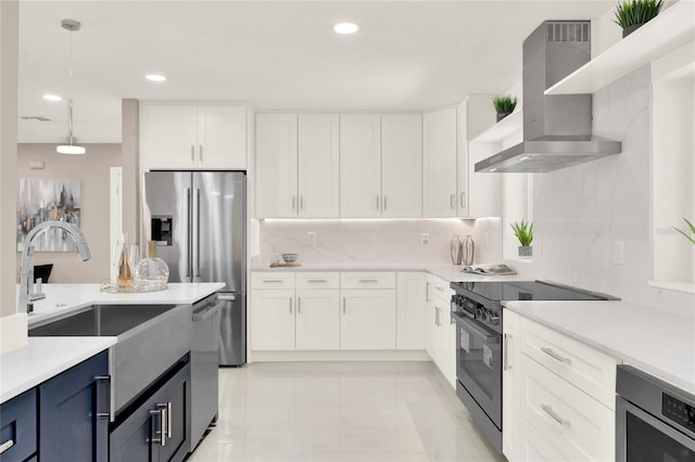 kitchen featuring decorative light fixtures, appliances with stainless steel finishes, white cabinets, and wall chimney exhaust hood