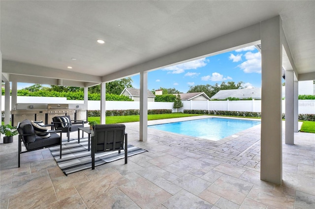 view of swimming pool featuring an outdoor kitchen and a patio