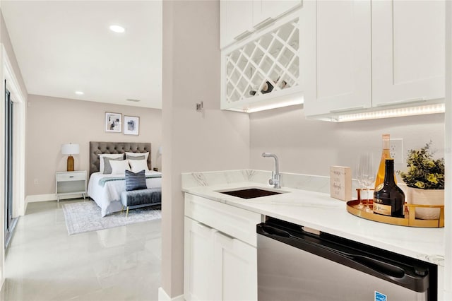 kitchen featuring stainless steel dishwasher, sink, light stone countertops, and white cabinets