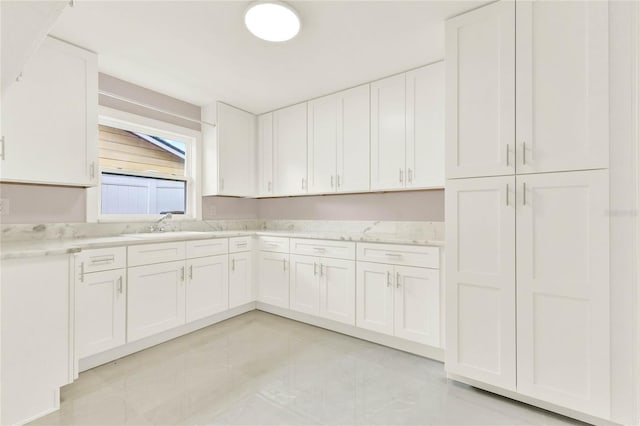 kitchen with white cabinetry, light stone counters, and light tile patterned floors