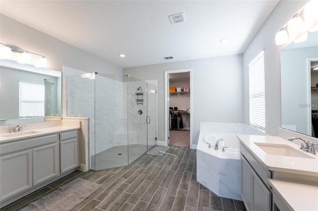 bathroom with plus walk in shower, vanity, and a wealth of natural light