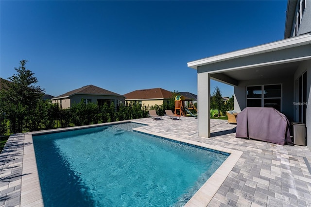 view of swimming pool featuring a patio, a playground, and a grill