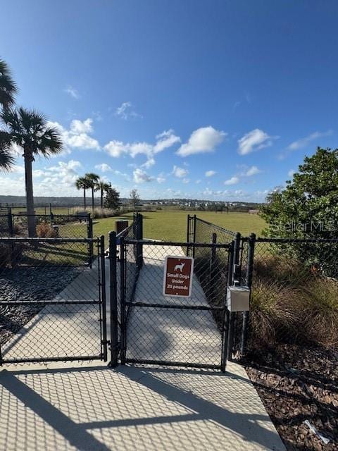 view of gate featuring a lawn and a rural view