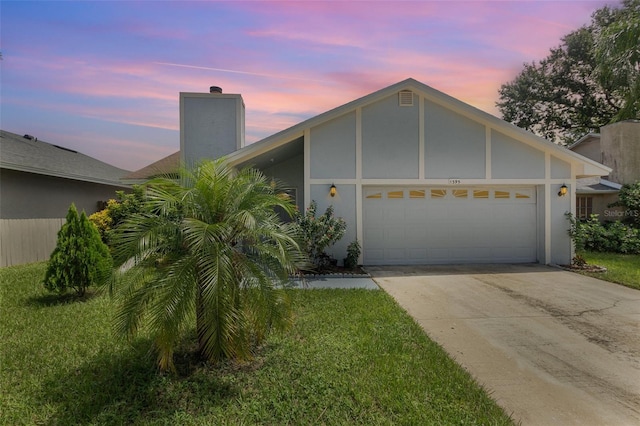 view of front of house with a yard, stucco siding, driveway, and a garage