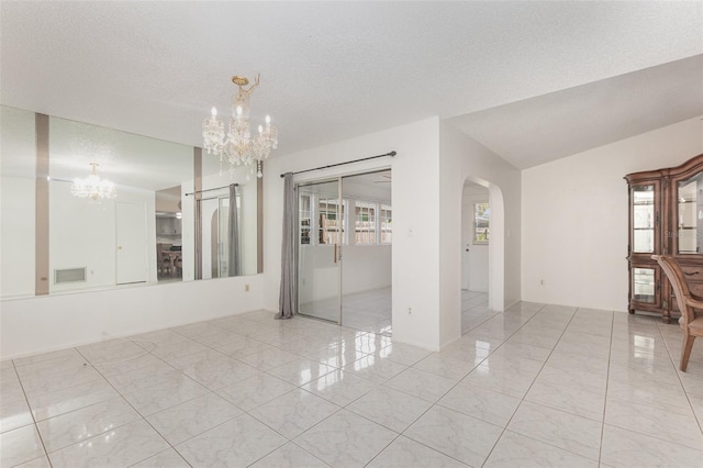 empty room featuring a textured ceiling, a notable chandelier, and a healthy amount of sunlight