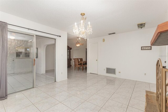 interior space featuring ceiling fan with notable chandelier, a textured ceiling, and light tile patterned flooring