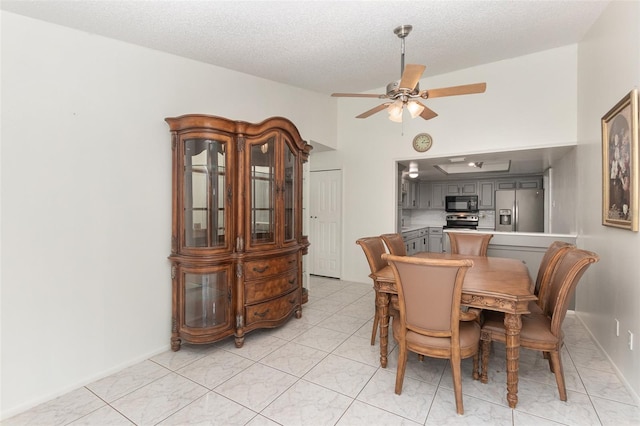 tiled dining room with a textured ceiling and ceiling fan