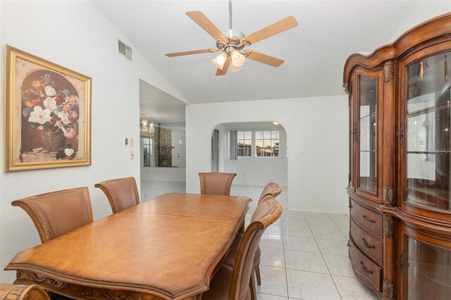 dining room featuring ceiling fan with notable chandelier, vaulted ceiling, and light tile patterned floors