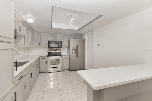 kitchen featuring gray cabinetry, appliances with stainless steel finishes, a tray ceiling, sink, and light tile patterned flooring