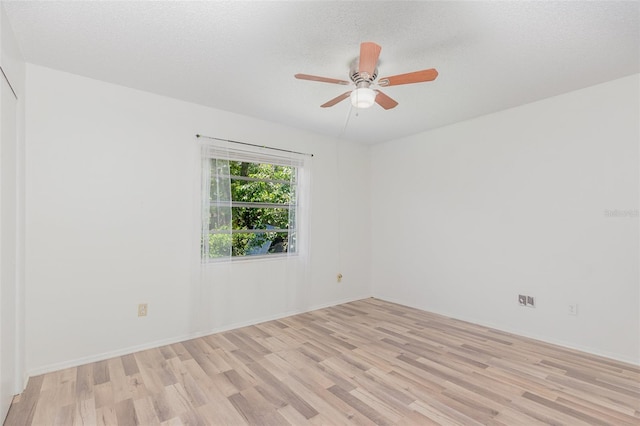 spare room featuring light wood-type flooring, a textured ceiling, and ceiling fan