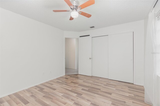 unfurnished bedroom with a textured ceiling, light hardwood / wood-style flooring, and ceiling fan