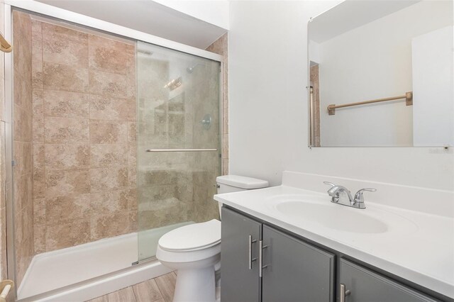 bathroom featuring vanity, toilet, wood-type flooring, and walk in shower