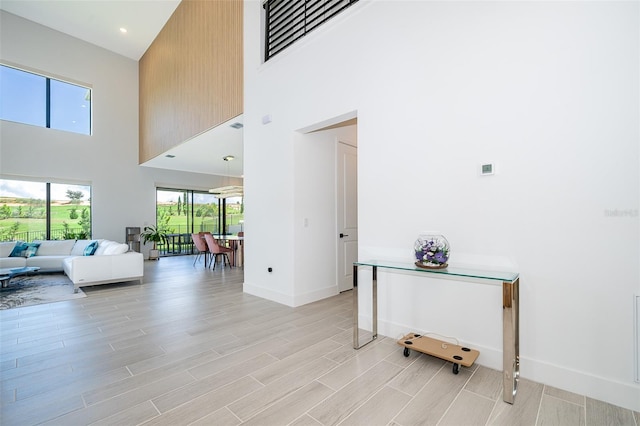 hall featuring a towering ceiling and light hardwood / wood-style flooring