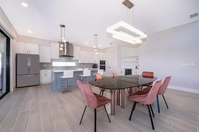 dining room featuring a notable chandelier, sink, wine cooler, and light hardwood / wood-style flooring