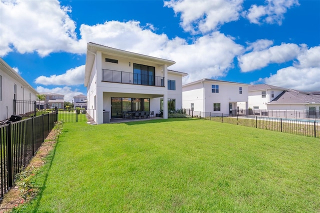 back of property with a balcony, a yard, and a patio area