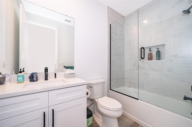 full bathroom with combined bath / shower with glass door, vanity, toilet, and hardwood / wood-style floors