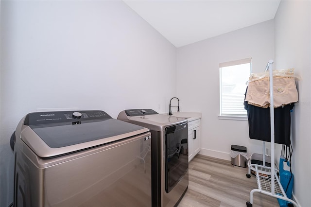 laundry area featuring light wood-type flooring, sink, cabinets, and separate washer and dryer