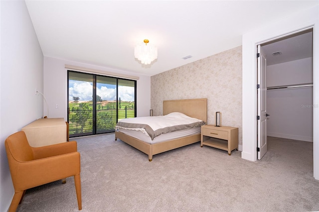 carpeted bedroom with access to exterior and a chandelier