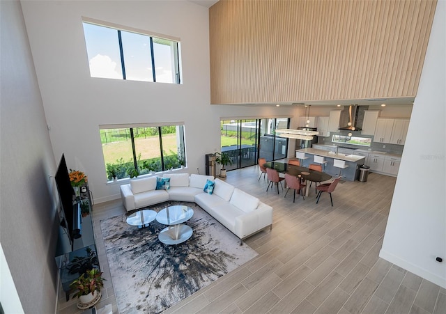 living room featuring a high ceiling, plenty of natural light, and light hardwood / wood-style flooring