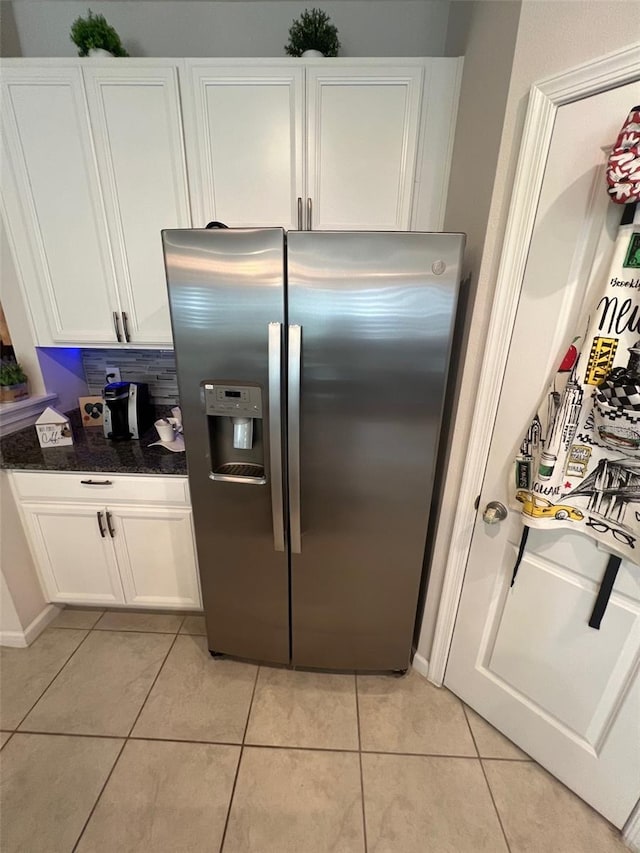 kitchen with dark stone countertops, light tile patterned floors, white cabinetry, and stainless steel refrigerator with ice dispenser