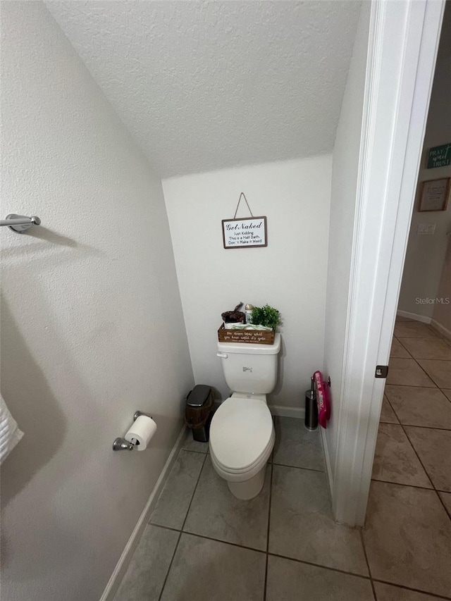 bathroom with tile patterned flooring, toilet, vaulted ceiling, and a textured ceiling