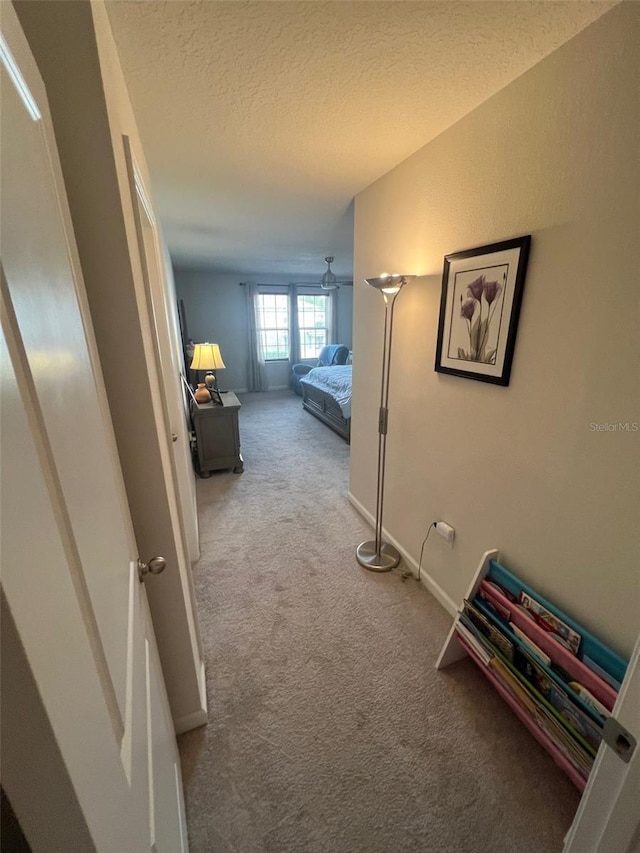 corridor featuring a textured ceiling, light colored carpet, and lofted ceiling